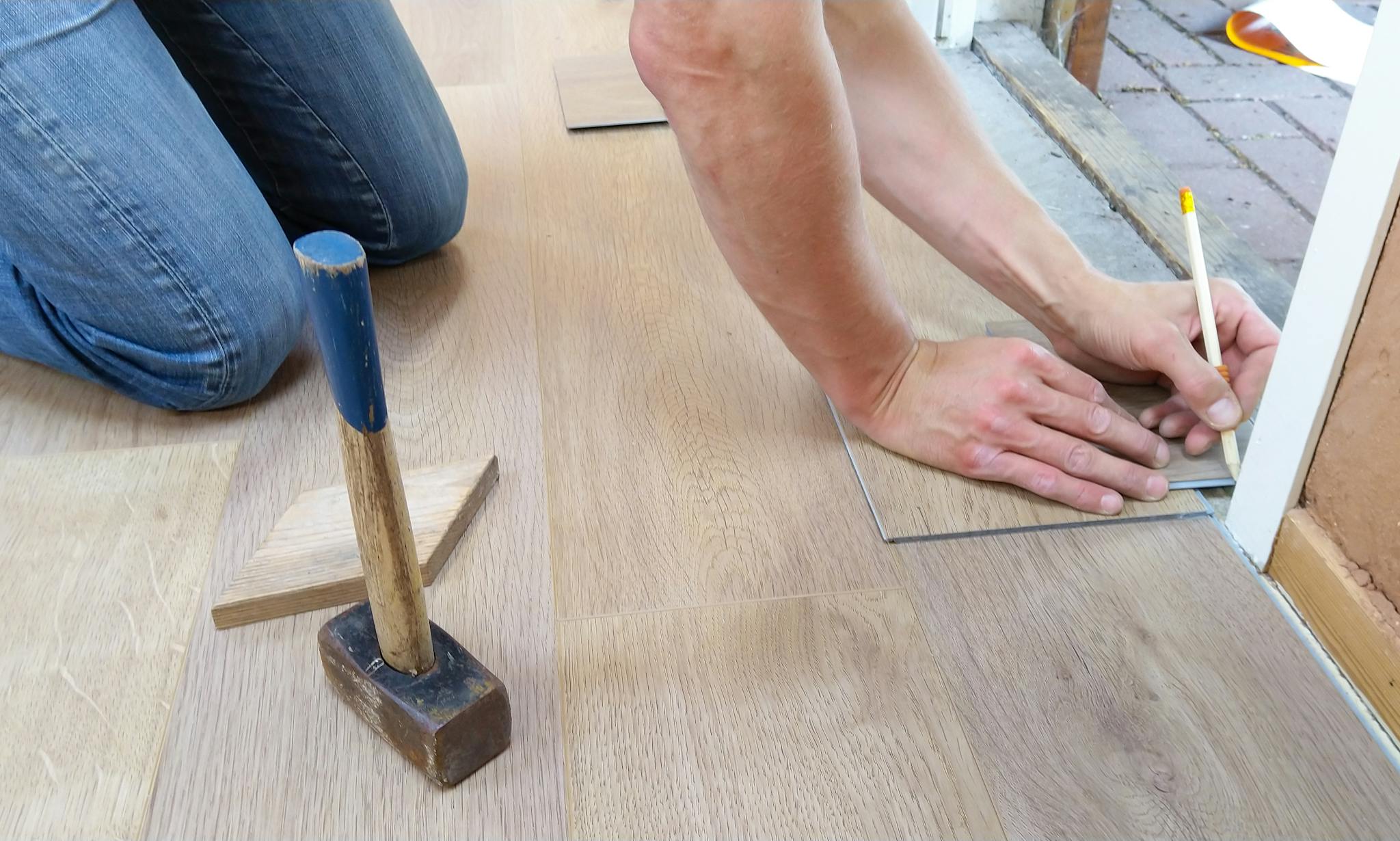 Craftsman measuring and marking wood floor panels before installation