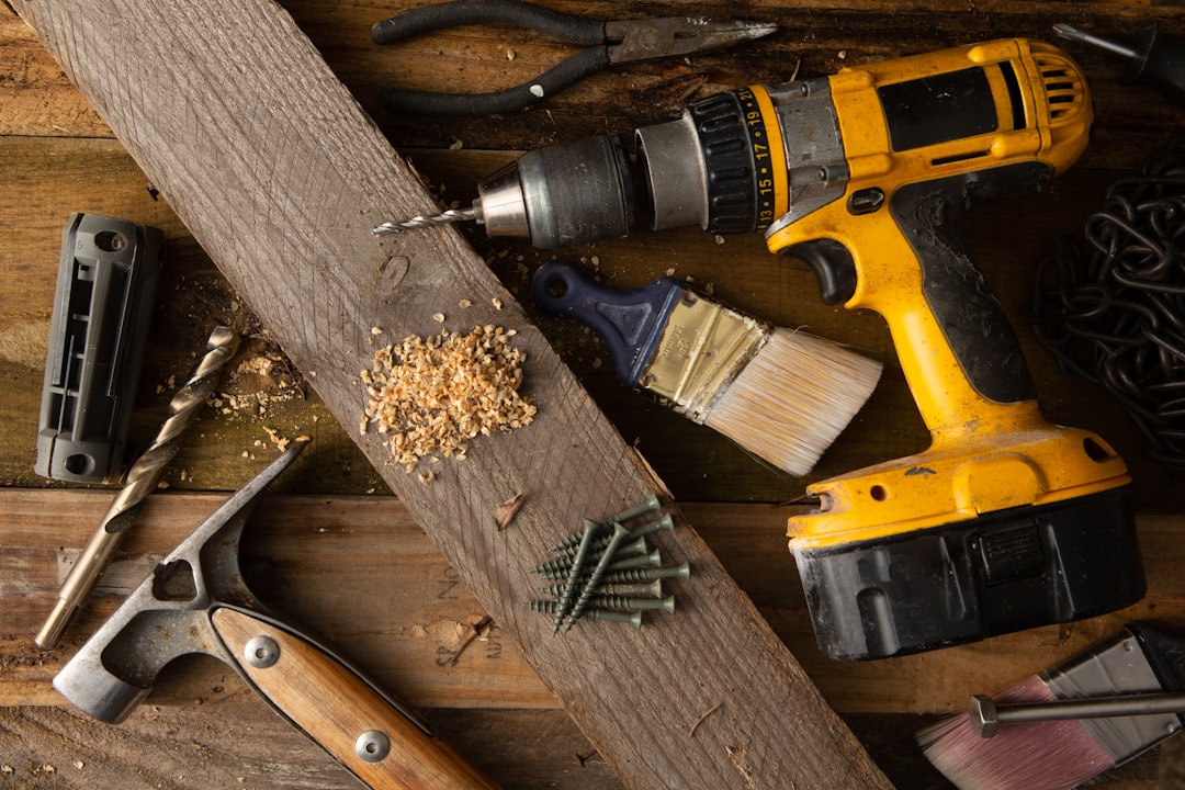 Cordless drill and hand tools laid out on a wooden work surface