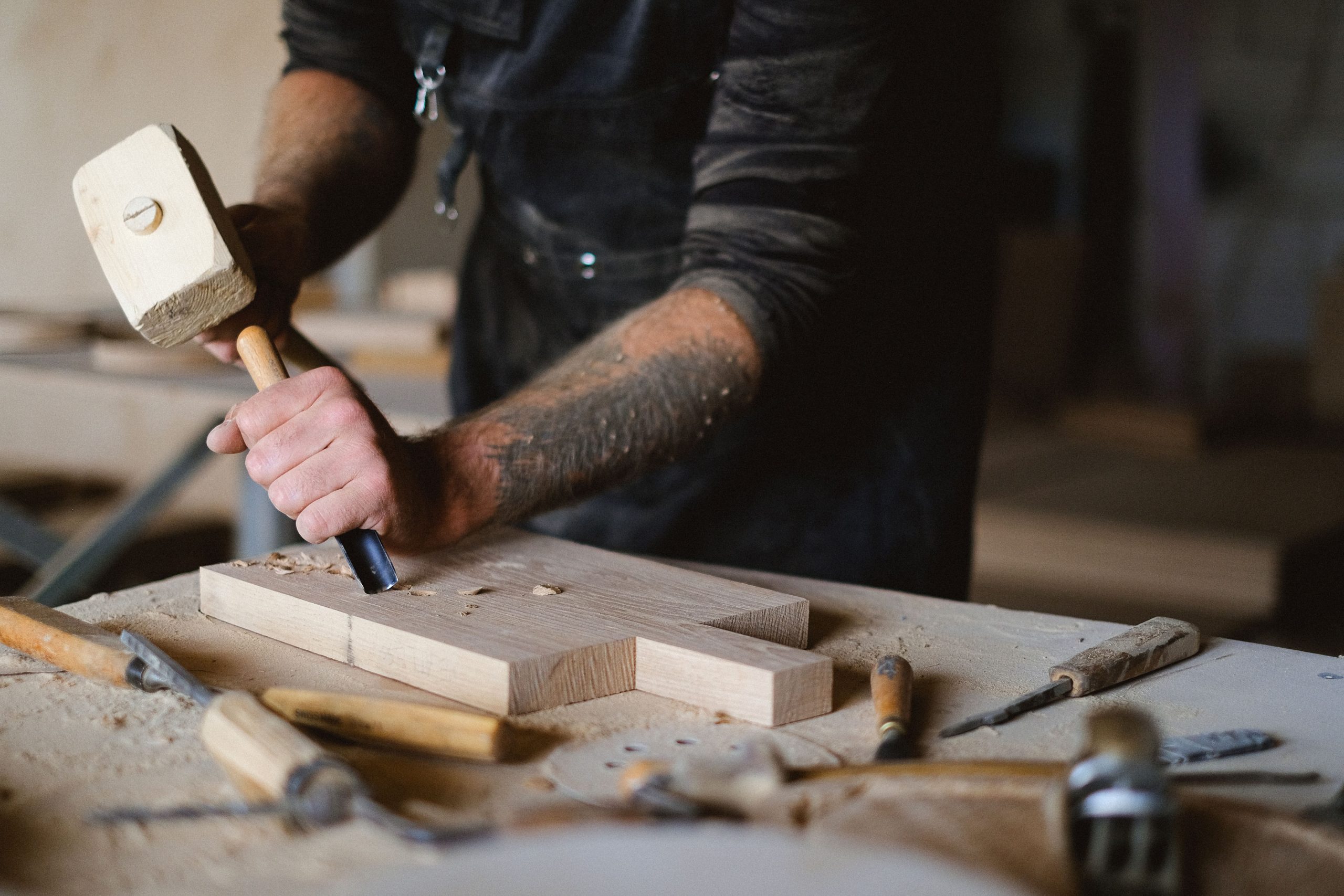 Carpenter carving wood with a chisel and mallet.