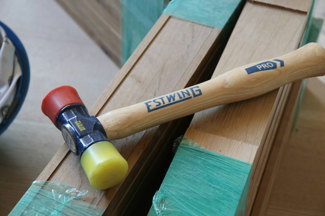 Soft-face mallet with red and yellow striking faces resting on bundled wood boards