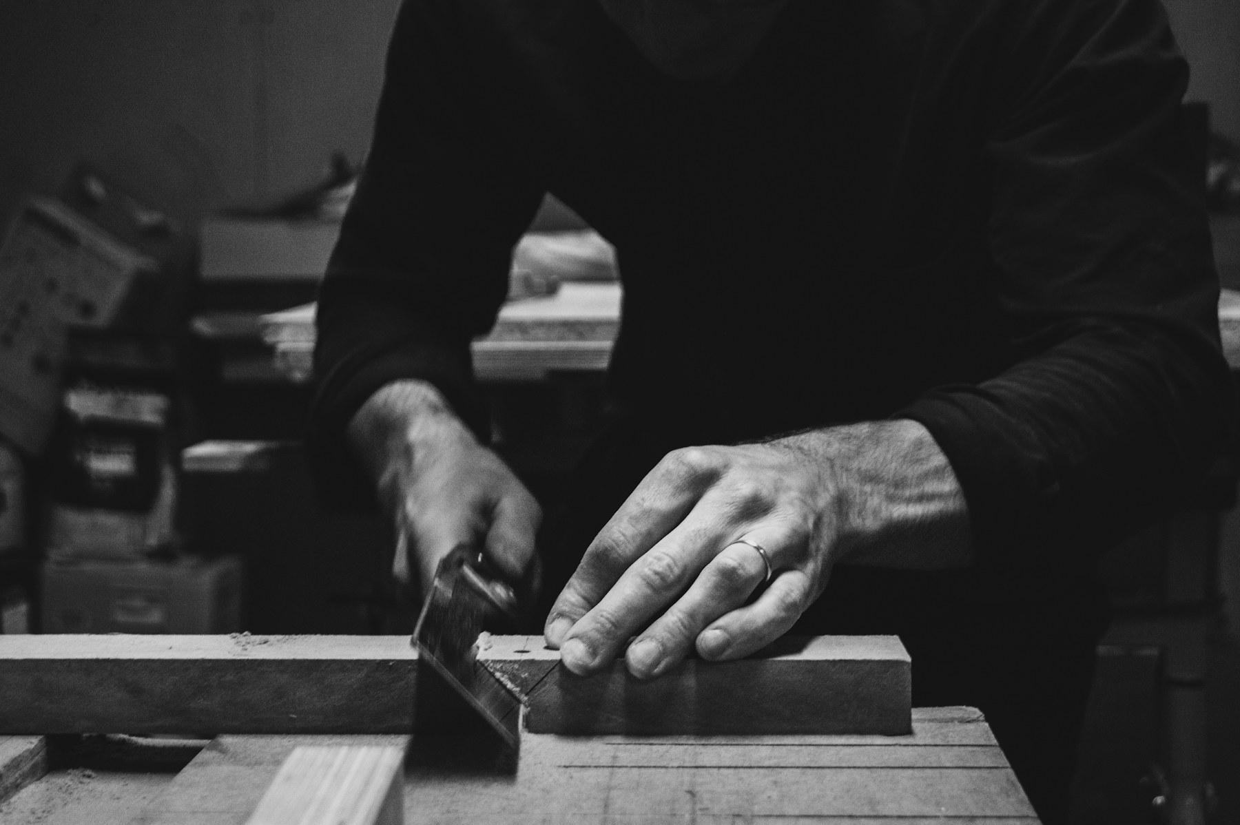 Carpenter guiding a wood board through a table saw at a cut station